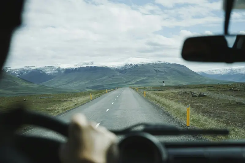 Driver at the wheel, mountain road seen from the cab